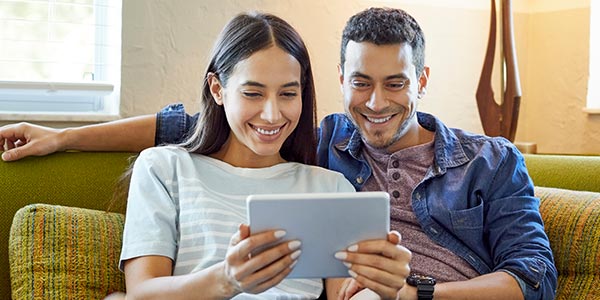 happy couple on sofa with tablet